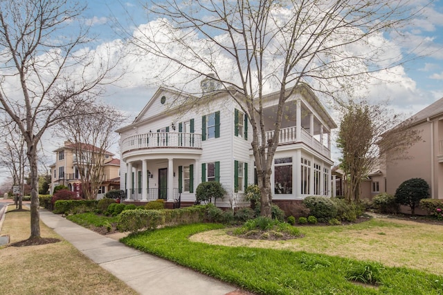 view of front of house featuring a balcony and a front lawn