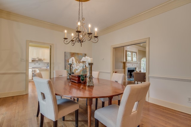 dining room with a fireplace, light wood-type flooring, baseboards, and ornamental molding