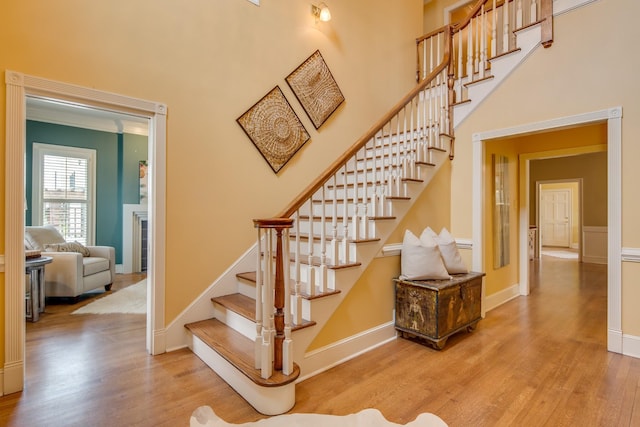 staircase featuring baseboards, a high ceiling, and wood finished floors