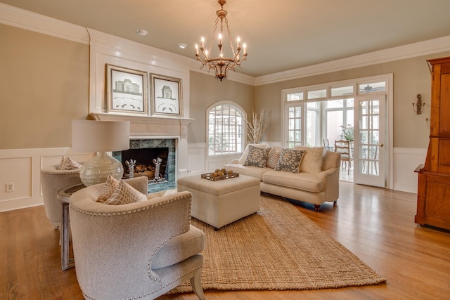 living area with a wainscoted wall, a fireplace, crown molding, and wood finished floors