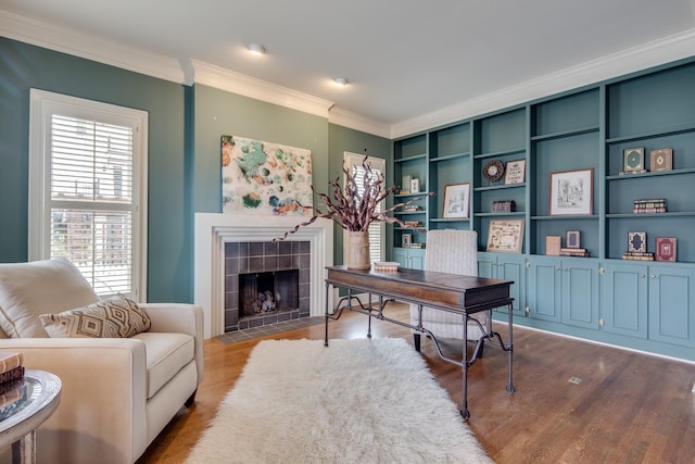 office featuring a tiled fireplace, crown molding, and wood finished floors