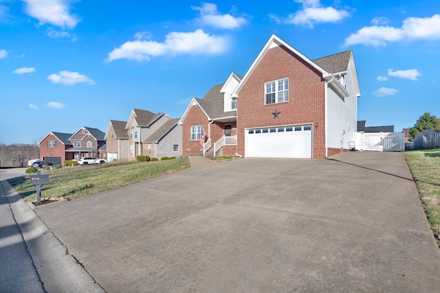 view of front facade with brick siding, a residential view, a garage, driveway, and a gate