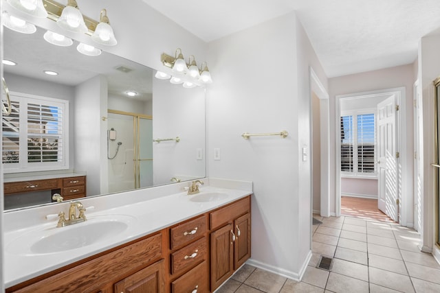 full bathroom with tile patterned floors, double vanity, a stall shower, and a sink