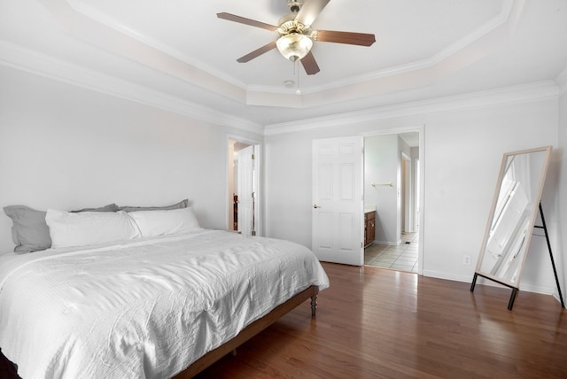 bedroom featuring a ceiling fan, a tray ceiling, wood finished floors, crown molding, and baseboards