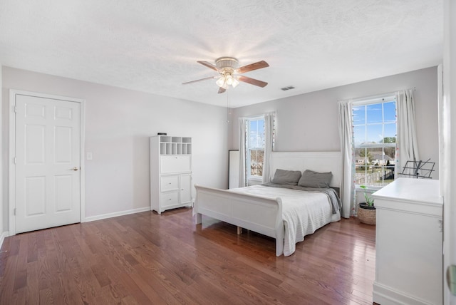 bedroom with multiple windows, a textured ceiling, wood finished floors, and a ceiling fan