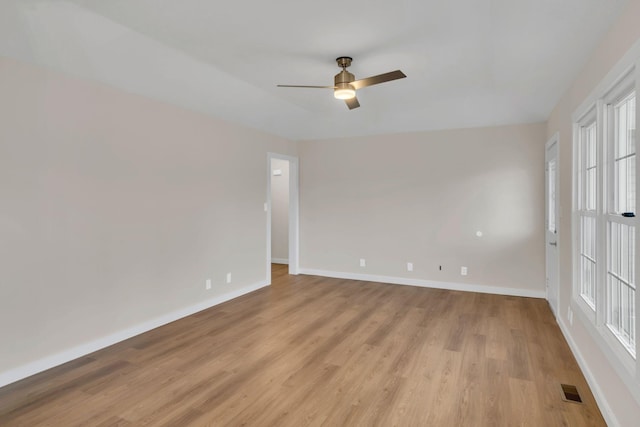 spare room with a ceiling fan, light wood-style floors, visible vents, and baseboards