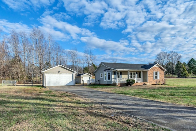 single story home with an outbuilding, a detached garage, covered porch, a front yard, and brick siding