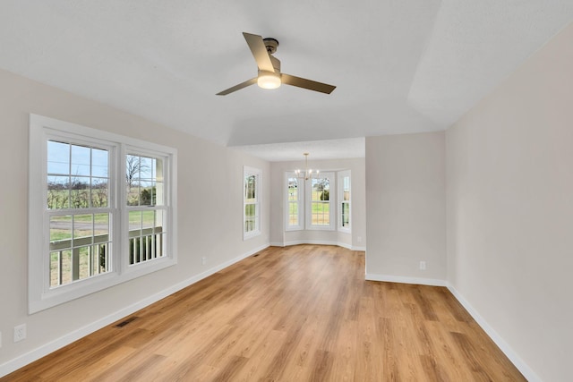 unfurnished room with visible vents, light wood-style flooring, ceiling fan with notable chandelier, and baseboards