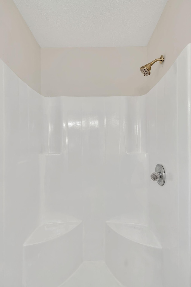 full bathroom featuring a shower and a textured ceiling