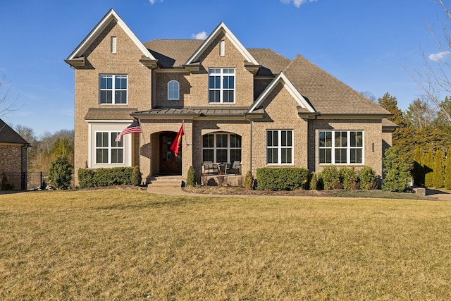 view of front of home featuring brick siding, a front lawn, and a shingled roof