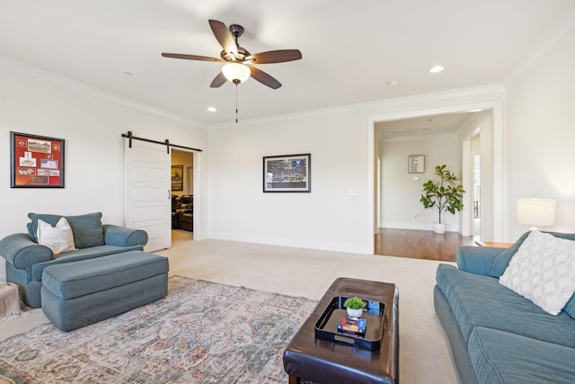 carpeted living room with ceiling fan, baseboards, a barn door, and ornamental molding