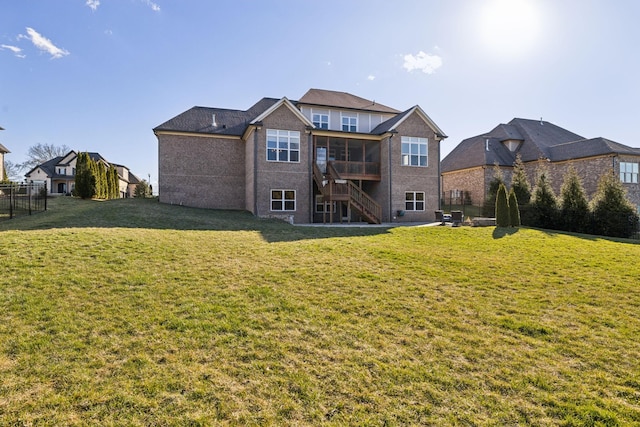 rear view of house with stairway, a lawn, and fence