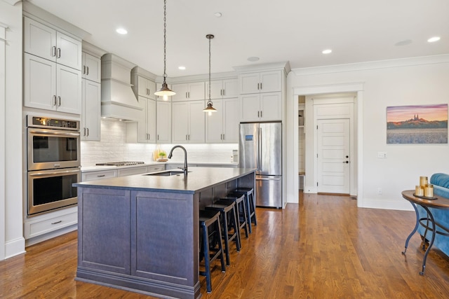 kitchen featuring custom exhaust hood, a sink, decorative backsplash, stainless steel appliances, and a kitchen breakfast bar