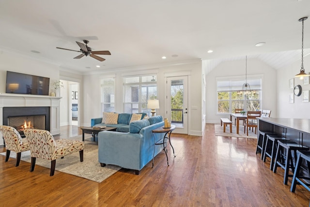 living room with ornamental molding, lofted ceiling, a lit fireplace, and dark wood-style flooring