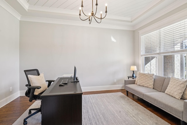 office space with dark wood-type flooring, baseboards, a chandelier, ornamental molding, and a raised ceiling