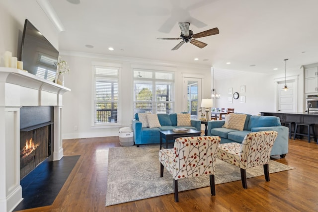 living room with crown molding, a fireplace with flush hearth, wood finished floors, and recessed lighting