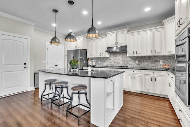 kitchen featuring dark wood finished floors, a sink, stainless steel appliances, white cabinets, and under cabinet range hood