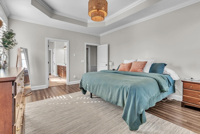 bedroom with connected bathroom, crown molding, baseboards, wood finished floors, and a raised ceiling