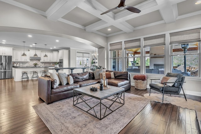 living area featuring beamed ceiling, wood-type flooring, coffered ceiling, and ceiling fan with notable chandelier