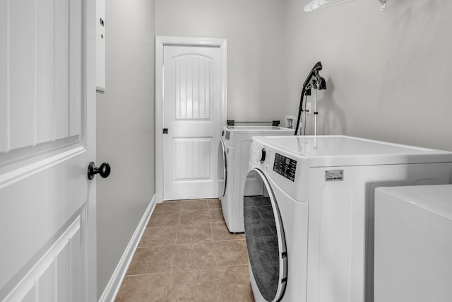 laundry area featuring light tile patterned floors, baseboards, washing machine and dryer, and laundry area