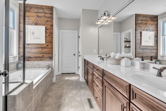 bathroom with a sink, visible vents, double vanity, and tiled bath