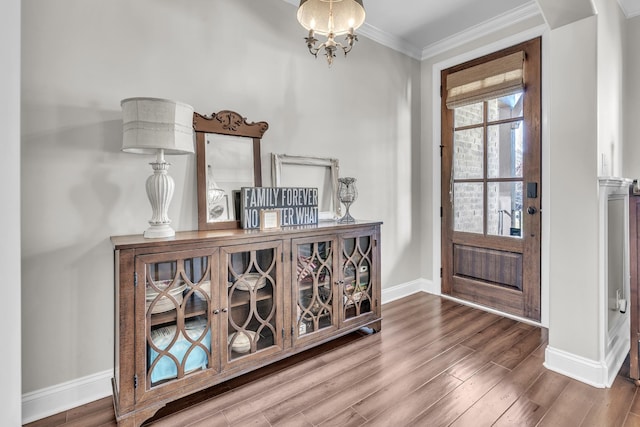 foyer entrance featuring crown molding, wood finished floors, baseboards, and a chandelier