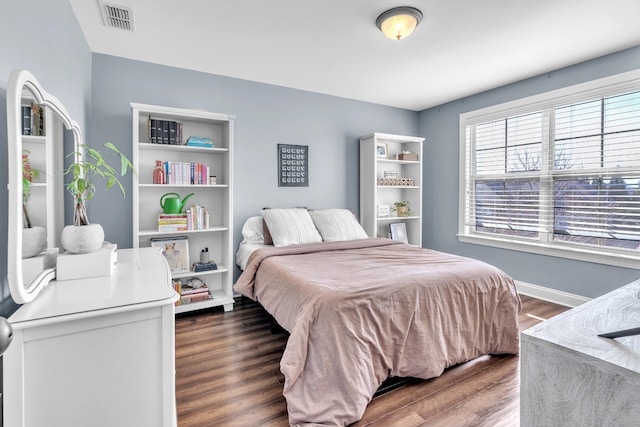 bedroom with visible vents, baseboards, and wood finished floors