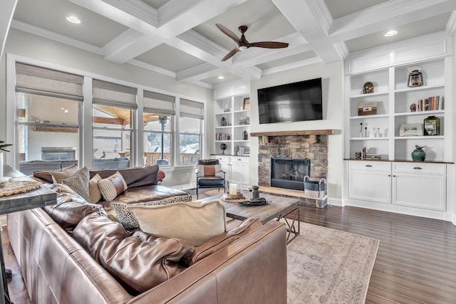 living area featuring dark wood-type flooring, ceiling fan, beam ceiling, a fireplace, and coffered ceiling