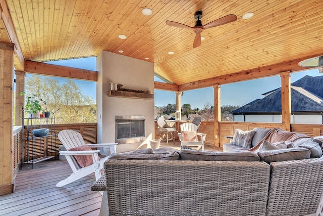 exterior space with a deck, an outdoor living space with a fireplace, outdoor dining area, and ceiling fan