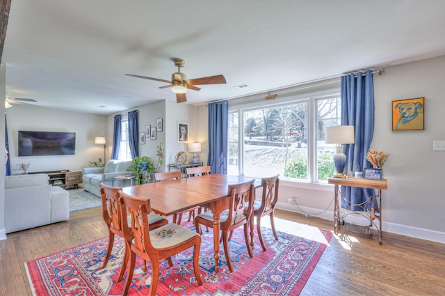 dining room featuring a ceiling fan, visible vents, wood finished floors, and baseboards