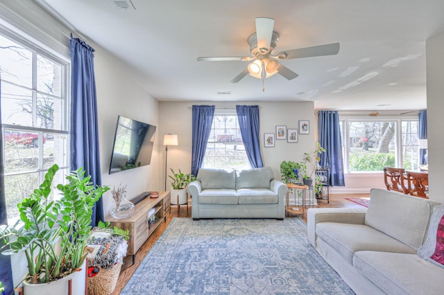 living room with a ceiling fan, wood finished floors, visible vents, and baseboards