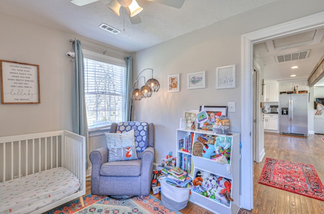 bedroom featuring visible vents, ceiling fan, stainless steel refrigerator with ice dispenser, and wood finished floors