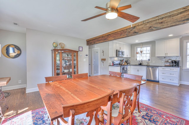 dining space with beam ceiling, light wood-style flooring, visible vents, and baseboards