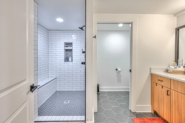 full bathroom with tile patterned floors, baseboards, vanity, and a shower stall