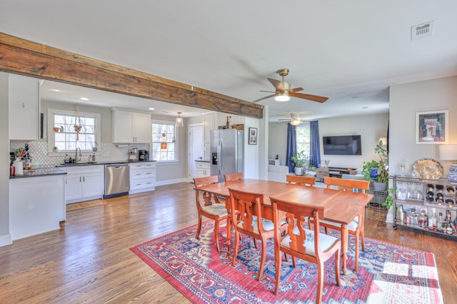 dining room with visible vents, beam ceiling, light wood-style floors, baseboards, and ceiling fan