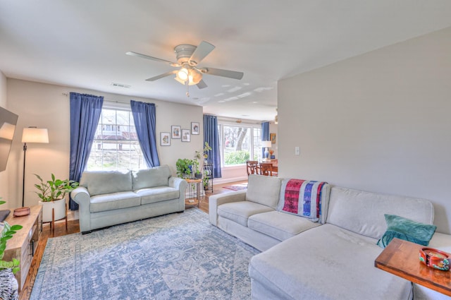 living area with visible vents, wood finished floors, and a ceiling fan