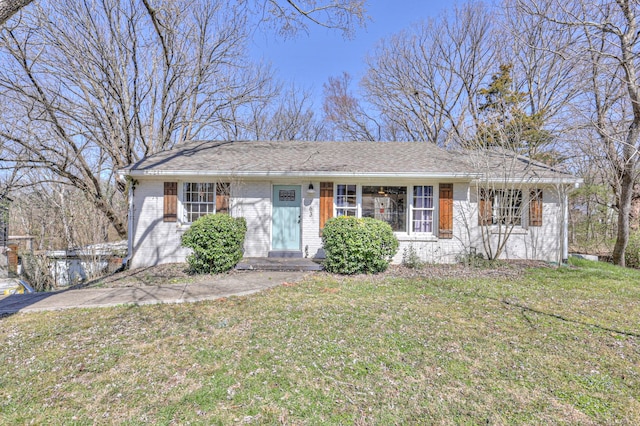 single story home featuring brick siding, a front yard, and a shingled roof