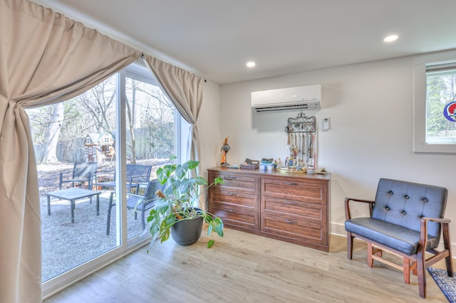 sitting room featuring an AC wall unit, recessed lighting, and wood finished floors