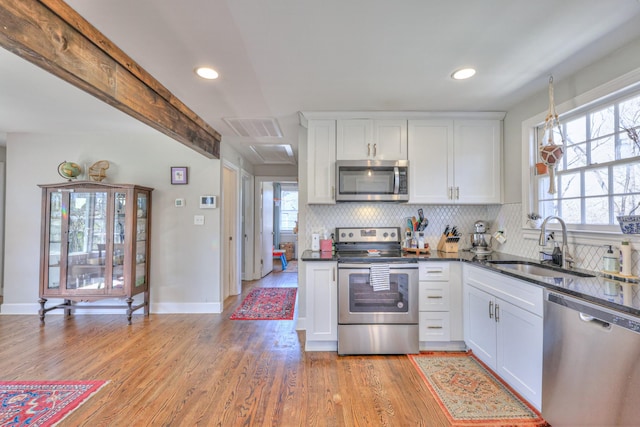 kitchen with light wood-type flooring, visible vents, a sink, tasteful backsplash, and appliances with stainless steel finishes