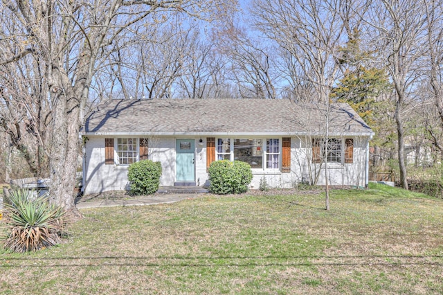 view of front of property featuring brick siding, roof with shingles, and a front yard