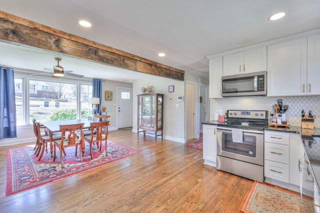 kitchen with light wood finished floors, recessed lighting, appliances with stainless steel finishes, white cabinetry, and tasteful backsplash