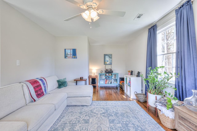 living area featuring visible vents, a ceiling fan, and wood finished floors