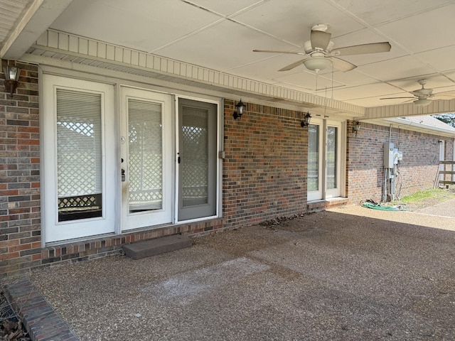 entrance to property with brick siding and a ceiling fan