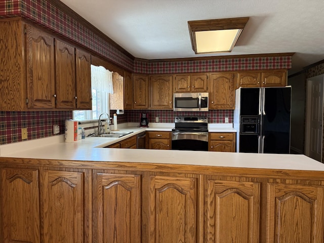 kitchen with a peninsula, a sink, light countertops, appliances with stainless steel finishes, and tasteful backsplash