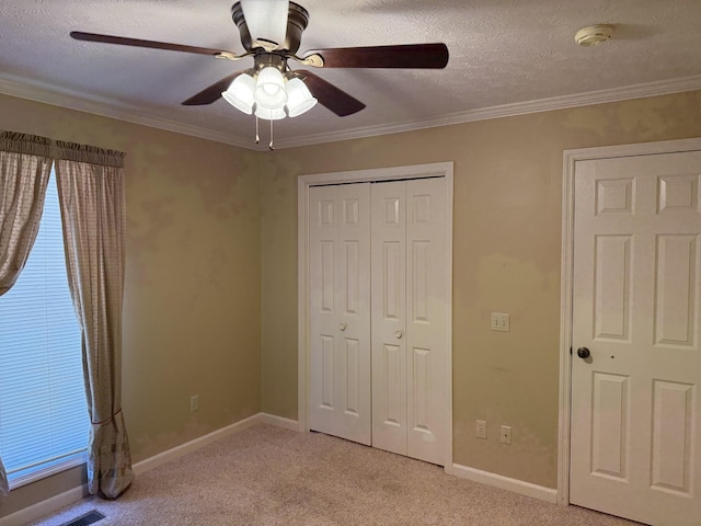 unfurnished bedroom featuring a closet, light colored carpet, a textured ceiling, and crown molding