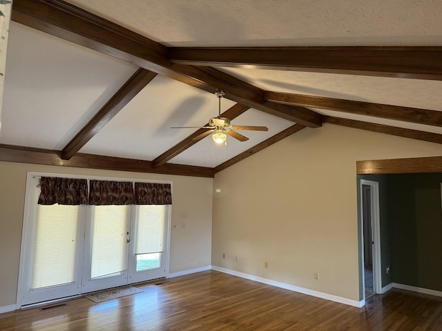 spare room with lofted ceiling with beams, wood finished floors, visible vents, and baseboards