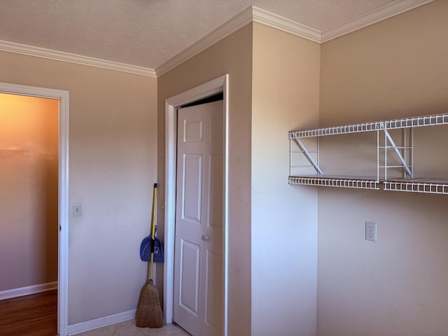 interior space with a textured ceiling, baseboards, and ornamental molding