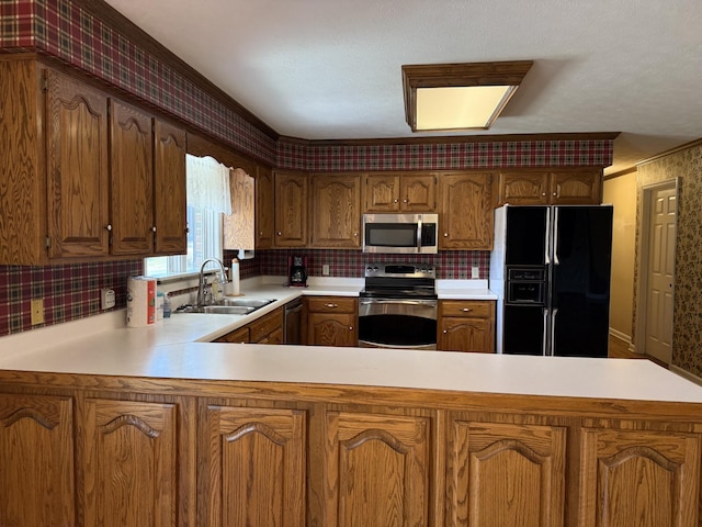 kitchen featuring a peninsula, a sink, decorative backsplash, light countertops, and appliances with stainless steel finishes