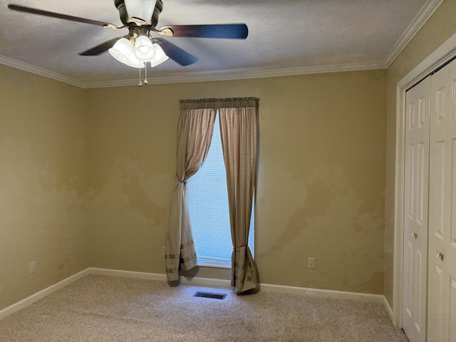 unfurnished room featuring visible vents, baseboards, ornamental molding, carpet flooring, and a textured ceiling