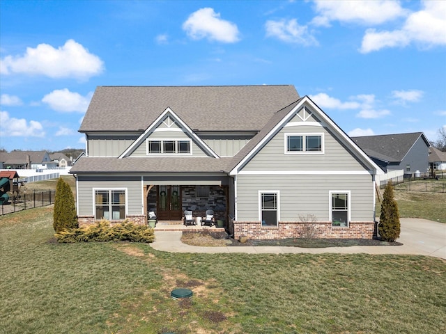 craftsman inspired home with brick siding, a front lawn, fence, roof with shingles, and french doors